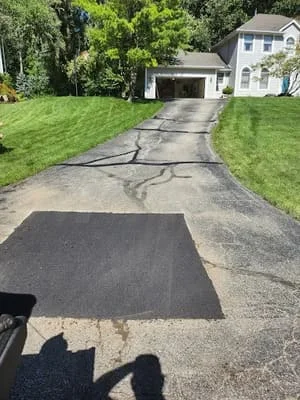 Newly sealcoated asphalt driveway with crack repairs and fresh black finish