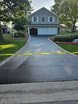Newly sealcoated asphalt driveway with dark black finish and clean edges