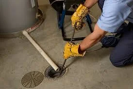 Technician cleaning parking lot drain line with debris removal and maintenance work