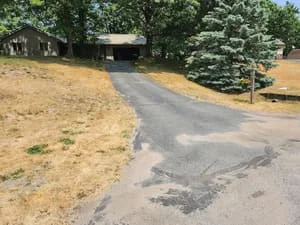 Residential driveway with fresh sealcoat and patched asphalt repairs