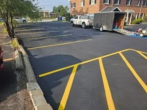 Newly sealcoated asphalt parking lot with bright yellow parking space lines and directional markings