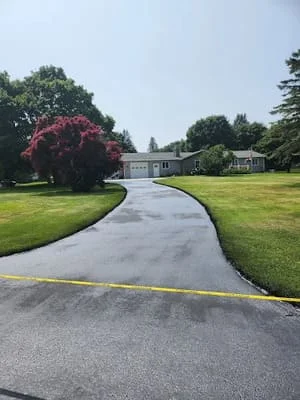 Curved asphalt driveway with manicured lawn and mature landscaping on residential property