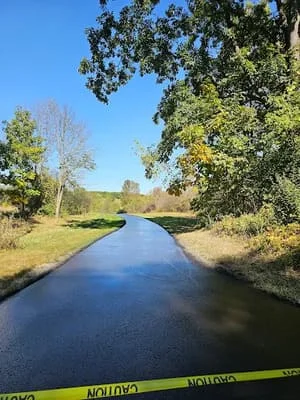 Newly paved asphalt canal pathway with mature trees and clear water reflection